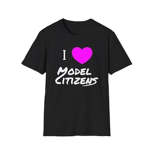 May include: A black short-sleeved t-shirt featuring a graphic print on the front. The design includes a white letter I, a bright pink heart symbol, and the white text "MODEL CITIZENS" written in a stylized, handwritten font below the heart.