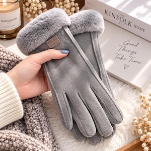 Może przedstawiać: Para szarych rękawiczek z miękkim mankietem ze sztucznego futra i małą prostokątną naszywką na wierzchu dłoni z napisem FASHION GLOVES. Rękawiczki mają gładkie, matowe wykończenie oraz widoczne szwy wzdłuż palców i części dłoniowej.