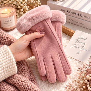 Può includere: Un paio di guanti rosa polvere con un morbido polsino in ecopelliccia e una piccola etichetta rettangolare sul dorso della mano con il testo Fashion Gloves. I guanti presentano una consistenza liscia simile al camoscio e cuciture visibili sulle dita.