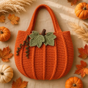Pode incluir: Uma bolsa tote de crochê laranja brilhante em forma de abóbora, com textura canelada vertical, duas alças resistentes e folhas e gavinhas de crochê verdes decorativas presas ao centro da parte superior da bolsa.