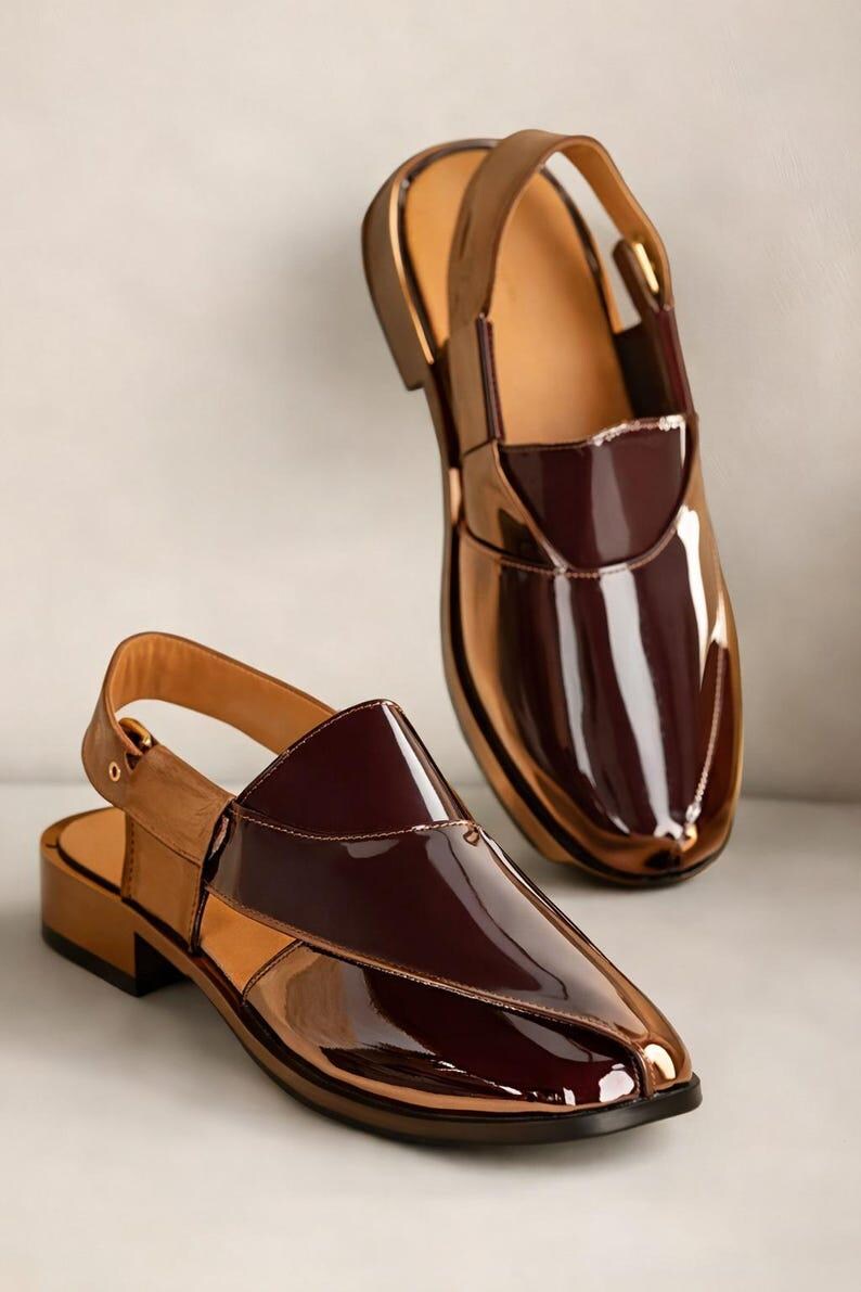 May include: A pair of glossy, two-tone shoes with a slingback design. The shoes feature a rich burgundy vamp and a metallic bronze-coloured body. The soles are a dark brown, and the shoes have a low heel.