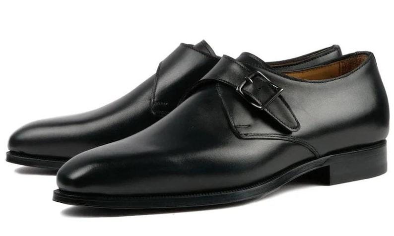 May include: A pair of black leather monk strap shoes. These shoes have a single buckle fastening and a polished finish. The design is classic, suitable for formal or business wear. The shoes are approximately 30 cm long.