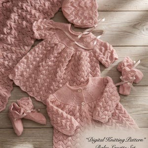 Puede incluir: Un conjunto de canastilla para bebé en rosa suave, que incluye un vestido, cárdigan, gorro, patucos y manta. El conjunto está tejido con un patrón texturizado y tiene un tamaño de 30-46 cm.