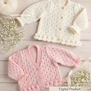 Op de afbeelding: Twee babyvesten, één crème en één roze, worden getoond. Het crèmekleurige vest heeft een ronde hals en gouden knopen. Het roze vest heeft een V-hals en zilveren knopen. Beide hebben een gefranjerde zoom en mouwen. De maat is 40.6-66 cm.