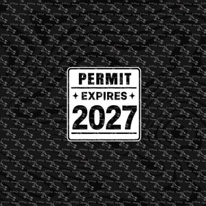 May include: A black and white sign with the text "PERMIT EXPIRES 2027" is set against a black background with a repeating pattern of small white illustrations. The sign is rectangular with a white border.
