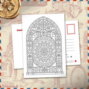 May include: A white postcard featuring a black and white line art illustration of a stained glass window with holiday motifs including snowflakes, bells, lanterns, and gift boxes, with a circular mandala pattern at the centre of the arch.