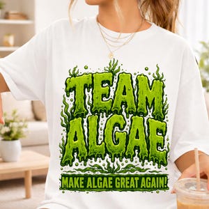 Peut inclure: Un t-shirt blanc avec une impression graphique affichant le texte "TEAM ALGAE" en grandes lettres vert citron dégoulinantes. En dessous, le texte "MAKE ALGAE GREAT AGAIN!" apparaît dans une police vert citron plus petite, entouré de motifs d'algues.