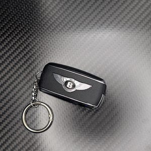 Peut inclure: Un porte-clés de voiture Bentley noir avec un porte-clés argenté. Le porte-clés présente un logo Bentley argenté avec des ailes et la lettre "B". Le porte-clés est en cuir noir et possède une garniture argentée.