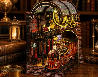 May include: A detailed, multi-layered wooden model of a train station with a steam train. The model features a brick facade, arched windows, and a clock tower. The word "TRAIN" is visible on a sign. The train is red and black.