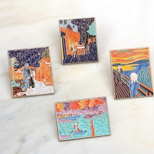 May include: Four rectangular enamel pins featuring famous art pieces. The pins depict scenes from Van Gogh's "Starry Night" and "Cafe Terrace at Night", along with Edvard Munch's "The Scream" and a boat scene. Each pin has a silver-colored border.