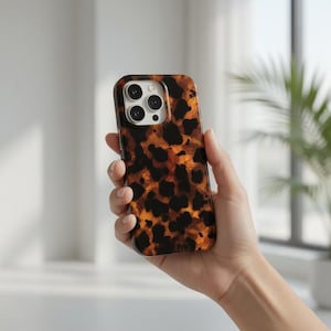 May include: A smartphone case with a tortoiseshell pattern. The case features a glossy finish with a repeating pattern of dark brown spots on a light brown background. The case has a camera cutout with three lenses.