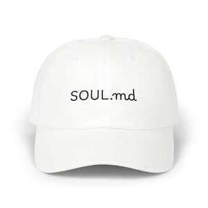 May include: A white baseball cap featuring the black text "SOUL.md" across the front. The cap has a curved peak and a rounded crown. The hat is made of a smooth, solid white material.