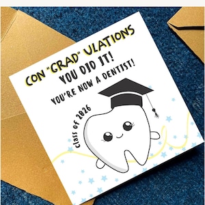 Puede incluir: Tarjeta de felicitaci&oacute;n blanca con el texto "CON 'GRAD' ULATIONS YOU DID IT! YOU'RE NOW A DENTIST!" en negro y amarillo. Un diente de dibujos animados con birrete. Fondo azul con estrellas.