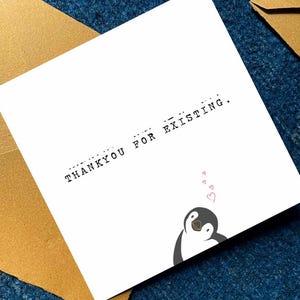 May include: A square white greeting card featuring the black text THANKYOU FOR EXISTING with Morse code dots and dashes above the letters. A small illustration of a penguin with three pink hearts floating above its head is in the corner.