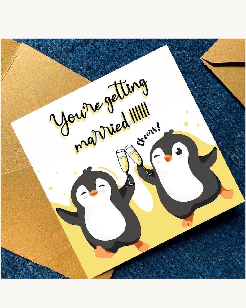 May include: A square greeting card featuring two cartoon penguins on a yellow background. The penguins are holding champagne flutes and the text reads: You're getting married!!!!!! Cheers! The card is accompanied by a gold-colored envelope.