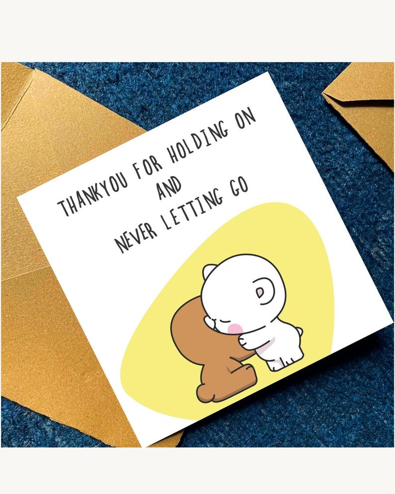 May include: A greeting card with the text "THANKYOU FOR HOLDING ON AND NEVER LETTING GO". The card features a cartoon illustration of two bear-like characters hugging on a yellow background.