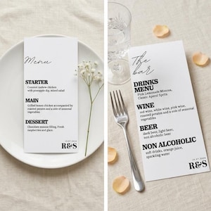 May include: Two white menu cards with black text. One card reads "Menu" and lists a starter, main course, and dessert. The other card reads "The Bar" and lists drinks, wine, beer, and non-alcoholic beverages. A fork and glass are visible.