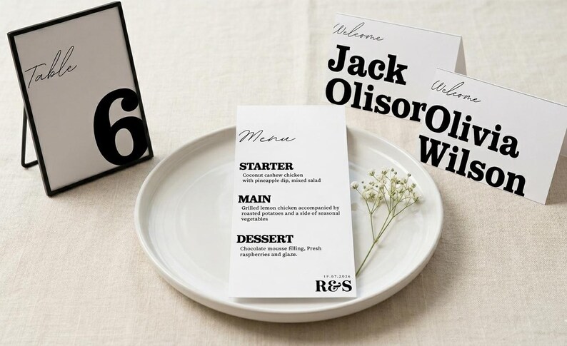 May include: A wedding table setting with a menu, place cards, and table number. The menu lists starter, main, and dessert options. Place cards read "Welcome Jack Olisor" and "Welcome Olivia Wilson." Table number 6 is displayed.