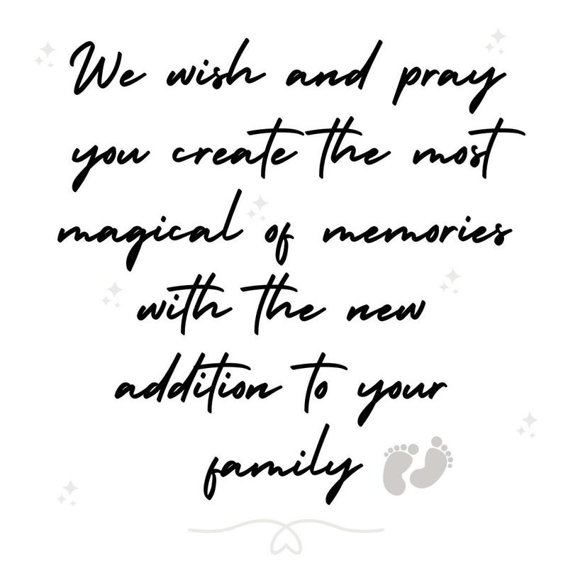May include: A white sign featuring black cursive text that reads: We wish and pray you create the most magical of memories with the new addition to your family. The design includes small grey star icons and a pair of grey baby footprints at the bottom.