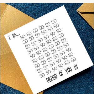 May include: A white card with the text "I AM... SO SO SO SO SO SO... PROUD OF YOU !!!" is placed inside a gold envelope, set against a dark blue textured background. The card's message is repeated multiple times.