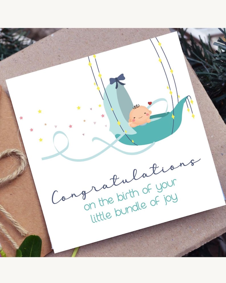 May include: A baby shower greeting card with a teal-colored baby carriage illustration. The card features the text "Congratulations on the birth of your little bundle of joy" in a handwritten font. The background is a neutral brown.