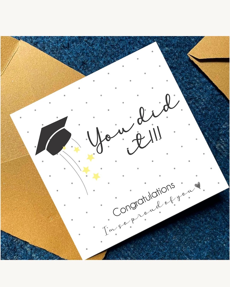 Peut inclure: Une carte de v&oelig;ux carr&eacute;e blanche avec une ic&ocirc;ne de toque de dipl&ocirc;m&eacute; noire, des &eacute;toiles jaunes et des points gris. Le texte indique : You did it!!! Congratulations I'm so proud of you. La carte est plac&eacute;e contre deux enveloppes dor&eacute;es.
