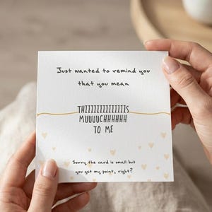 Puede incluir: Una tarjeta blanca con el texto "Just wanted to remind you that you mean THIIIIIIIIIIIIIIS MUUUUCHHHHHH TO ME." Peque&ntilde;as ilustraciones de corazones est&aacute;n dispersas por la tarjeta. Tambi&eacute;n se incluye el texto "Sorry the card is small but you get my point, right?"