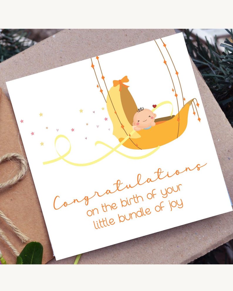 May include: A greeting card with a baby-themed illustration. The card features a cartoon baby in a yellow cradle, with the words "Congratulations on the birth of your little bundle of joy" written in orange script.