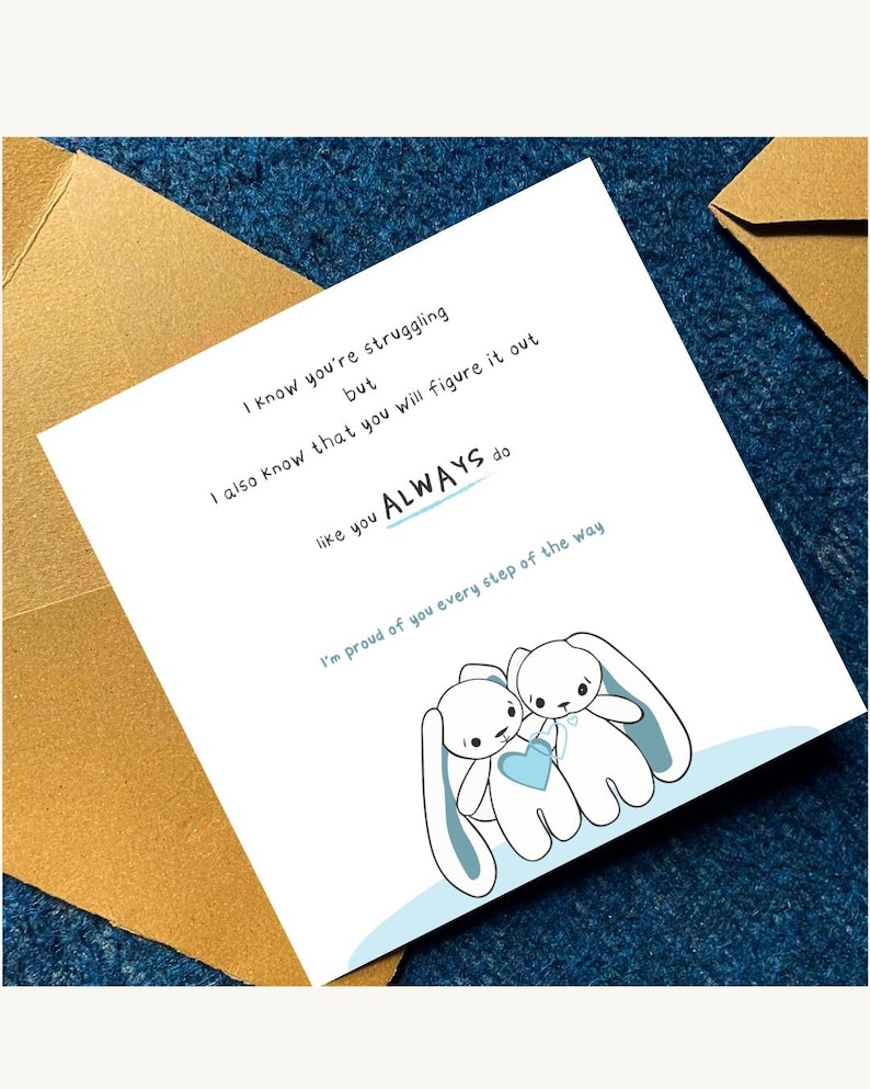 Peut inclure: Carte de v&oelig;ux blanche avec une bordure bleue et une illustration de deux lapins tenant un c&oelig;ur bleu. Le texte dit : &laquo; Je sais que tu as du mal, mais je sais aussi que tu vas t'en sortir comme tu le fais TOUJOURS. &raquo;