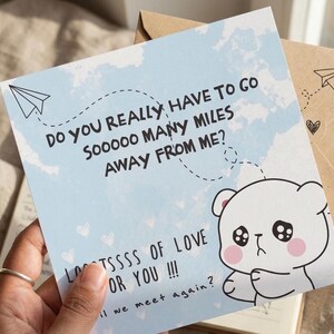 May include: A light blue greeting card with a sad bear illustration and the text "Do you really have to go so many miles away from me? Lots of love for you!!! Will we meet again?" A paper airplane is drawn on the card.