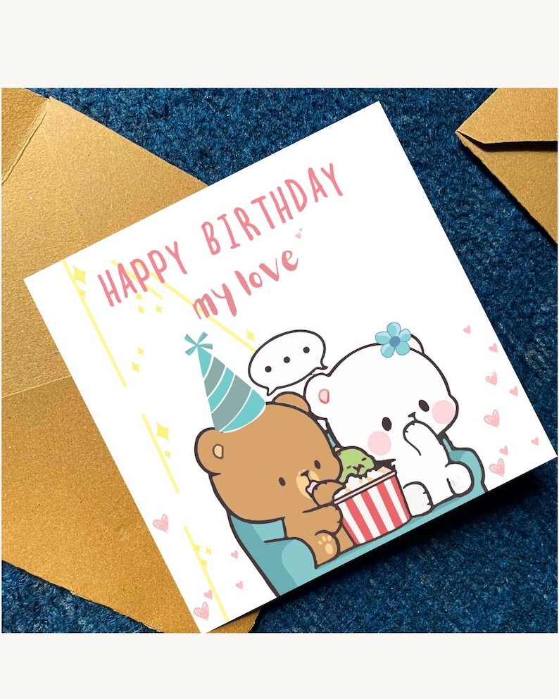 May include: A birthday greeting card with the text "HAPPY BIRTHDAY my love" in pink. The card features cartoon bears, one brown and one white, with a party hat and popcorn. The card is on a blue surface with a gold envelope.