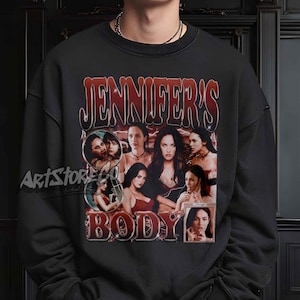 May include: Black crew neck sweatshirt with a graphic design. The design features the text "JENNIFER'S BODY" in red and white vintage lettering, along with multiple images of a woman. The sweatshirt is a classic style.