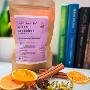 Peut inclure: Un sachet en papier brun avec l'inscription "Quiet Bookshop Simmer Kit", accompagné de tranches d'orange séchées, de bâtons de cannelle, d'anis étoilé et de fleurs de camomille. Le kit contient des ingrédients pour mijoter.