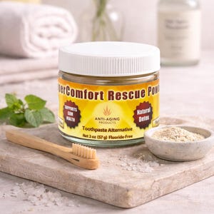 Könnte beinhalten: Ein Glas mit weißem Deckel, beschriftet mit "DerComfort Rescue Pow" und "Toothpaste Alternative". Daneben eine kleine Schale mit Pulver, eine Holzzahnbürste und ein Minzzweig. Das Glas enthält 57 g Produkt.