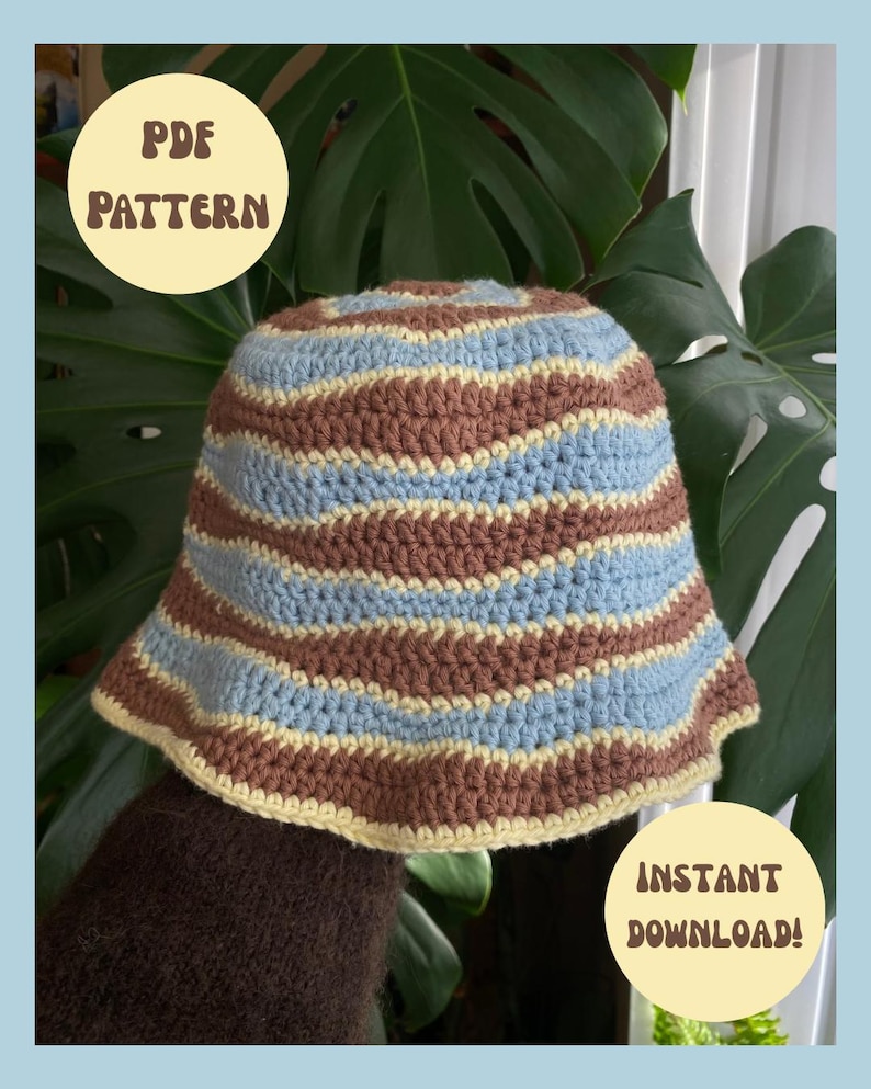 May include: A crochet bucket hat featuring horizontal wavy stripes in brown, light blue, and pale yellow. The hat has a circular crown and a downward-sloping brim. Text on the image reads PDF PATTERN and INSTANT DOWNLOAD!