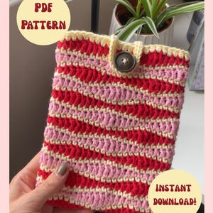 May include: A rectangular crochet pouch featuring horizontal stripes in red, light pink, and pale yellow yarn. The pouch has a pale yellow top edge with a central loop and a single dark brown button closure. Text reads PDF PATTERN and INSTANT DOWNLOAD.