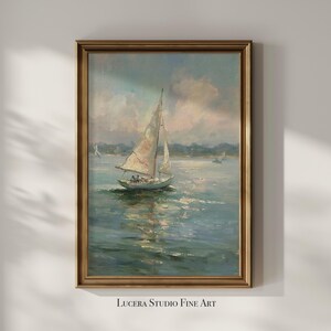 May include: A vertical framed oil painting depicting a sailboat on calm water under a soft, cloudy sky. The sailboat features a white sail and is positioned in the center of the composition. The frame is a metallic gold color with a classic profile.