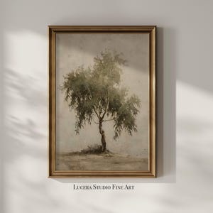 May include: A framed vintage-style print featuring a tree with green foliage and a slender trunk. The artwork has a muted color palette with a gold-colored frame. The text "Lucera Studio Fine Art" is printed at the bottom.