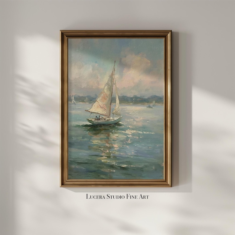 May include: A vertical framed oil painting depicting a sailboat on calm water under a soft, cloudy sky. The sailboat features a white sail and is positioned in the center of the composition. The frame is a metallic gold color with a classic profile.