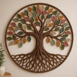 Puede incluir: Adorno de pared circular hecho a mano con un diseño de árbol de la vida. El árbol está hecho de hilo marrón con un tronco, raíces y ramas detallados. Las hojas están tejidas en varios colores, incluyendo verde, amarillo y rosa. La pieza está enmarcada por un borde circular marrón.