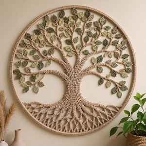 Puede incluir: Un tapiz de pared circular con un diseño de árbol tejido a ganchillo. El árbol tiene un tronco y ramas beige con hojas verdes y beige. Las raíces del árbol son visibles en la parte inferior, y el diseño está enmarcado por un círculo beige. Decoración del hogar.