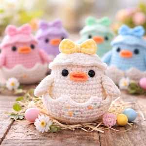 May include: Crocheted Easter chicks in pastel colors, each emerging from a decorative eggshell. The chicks have black eyes, orange beaks, and are adorned with bows. The scene includes decorative eggs and flowers on a wooden surface.