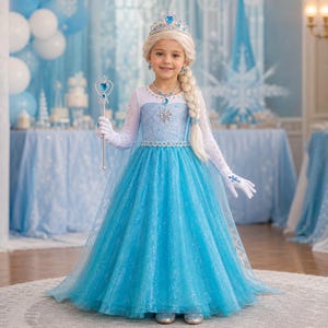 Könnte beinhalten: Ein bodenlanges hellblaues Kleid mit langen, transparenten Ärmeln, einem silbernen Paillettenoberteil und einem glitzernden Rock. Das Set enthält eine silberne Krone mit blauem Schmuckstein, ein passendes Zepter mit blauem Herz und weiße Handschuhe.
