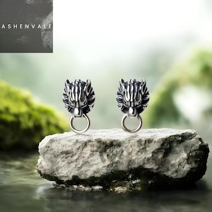 Puede incluir: Un juego de tres tazas de cerámica con un esmalte moteado de color crema. Cada taza presenta un diseño pintado a mano diferente: una hoja azul y verde, una flor amarilla y una baya roja. Las tazas tienen una forma simple y redondeada.