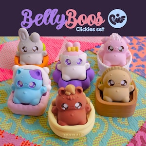 May include: A set of six colorful "Belly Boos Clickies" figurines. Each figurine is a different animal, including a bunny, pig, and bear, and is seated in a small, matching container. The text "Belly Boos Clickies set" is displayed at the top.