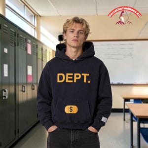 May include: Navy blue hoodie with the word "DEPT." in yellow block letters across the chest. A small yellow patch with the letter "S" is below the word. The hoodie has a front pocket and a drawstring hood. The background shows lockers and a classroom.