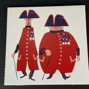 May include: Square ceramic tile featuring a whimsical illustration of two figures in red coats and blue hats, reminiscent of historical military attire. Each figure holds a cane and is adorned with medals. The artwork has a vintage, cartoonish style.
