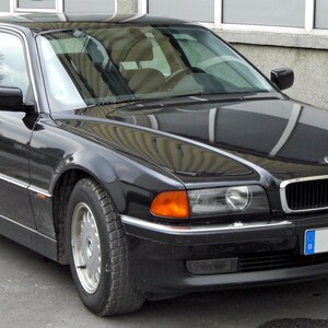 May include: A black BMW sedan with a shiny exterior. The car has a silver trim, a front license plate, and alloy wheels. The vehicle is parked on a paved surface.