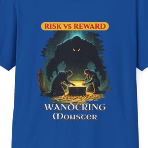 May include: Royal blue t-shirt featuring a fantasy-themed graphic. The design includes a large monster silhouette, two figures, and text that reads "RISK VS REWARD" and "WANDERING MONSTER" in a stylized font. The shirt is made of a soft material.