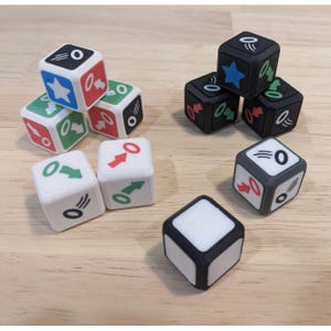 May include: A collection of ten six-sided dice featuring white and black bases. The dice display various colorful icons including stars, arrows, and circular rings with motion lines. Some dice are stacked in small groups, while others sit individually.
